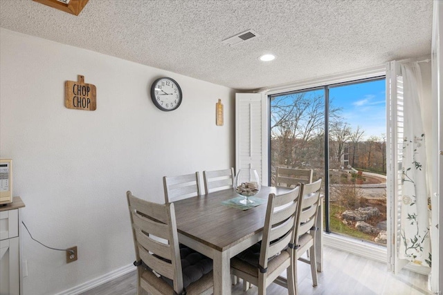 dining space featuring plenty of natural light, a textured ceiling, and light hardwood / wood-style flooring