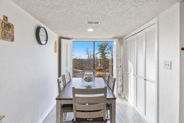 dining area featuring a textured ceiling and light hardwood / wood-style flooring