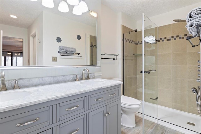 bathroom with hardwood / wood-style flooring, vanity, a tile shower, and a textured ceiling