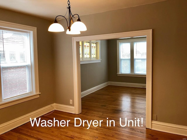 unfurnished room with a notable chandelier and dark wood-type flooring