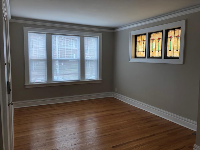 empty room with plenty of natural light, crown molding, and dark wood-type flooring