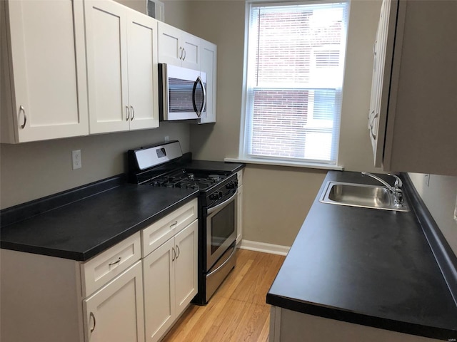 kitchen featuring white cabinetry, sink, stainless steel appliances, and light hardwood / wood-style flooring