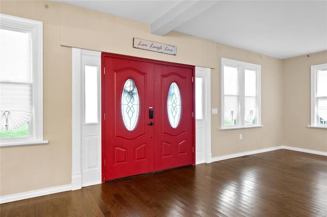 foyer entrance featuring a wealth of natural light, beamed ceiling, and dark wood-type flooring