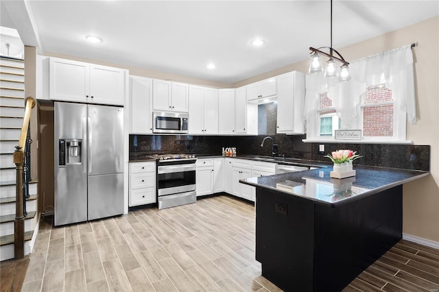 kitchen featuring decorative backsplash, stainless steel appliances, decorative light fixtures, and light hardwood / wood-style floors