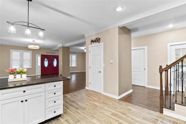 kitchen featuring decorative light fixtures, white cabinetry, dark stone countertops, and light hardwood / wood-style flooring