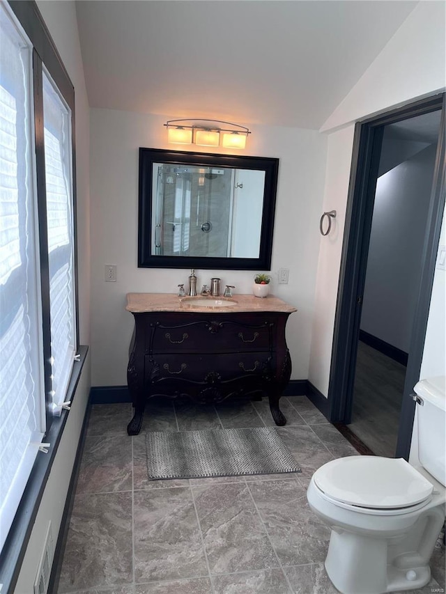 bathroom with toilet, vanity, and vaulted ceiling