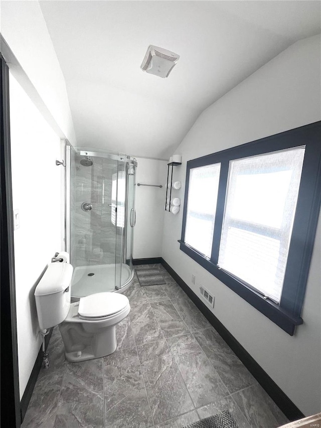 bathroom featuring toilet, vaulted ceiling, and a shower with shower door