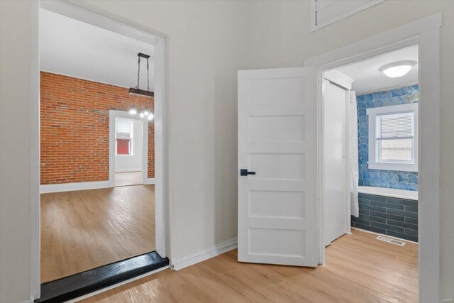 hallway featuring hardwood / wood-style floors and brick wall