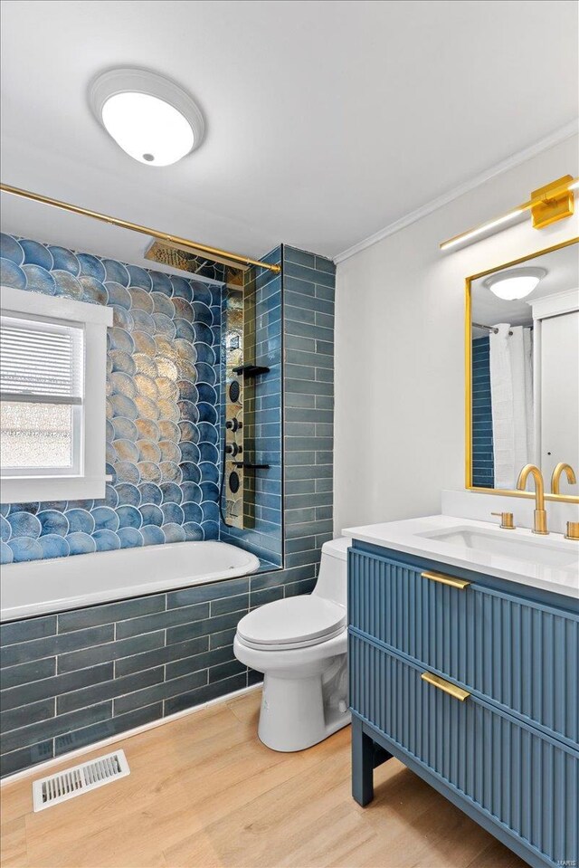 full bathroom featuring hardwood / wood-style flooring, vanity, toilet, and tiled shower / bath