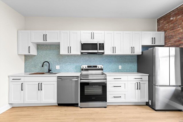 kitchen featuring appliances with stainless steel finishes, light hardwood / wood-style floors, white cabinetry, and sink