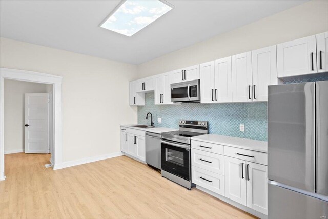 kitchen with white cabinetry, sink, stainless steel appliances, and light hardwood / wood-style floors