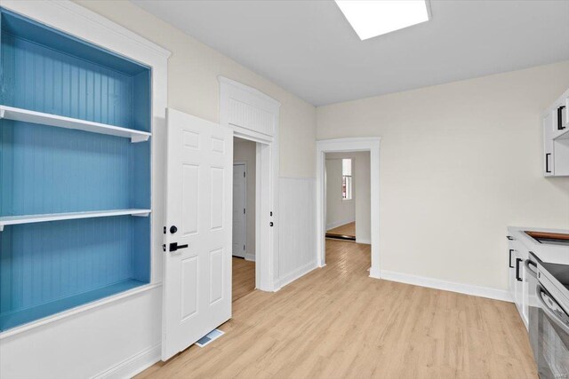 kitchen with white cabinets, light hardwood / wood-style floors, and stainless steel stove