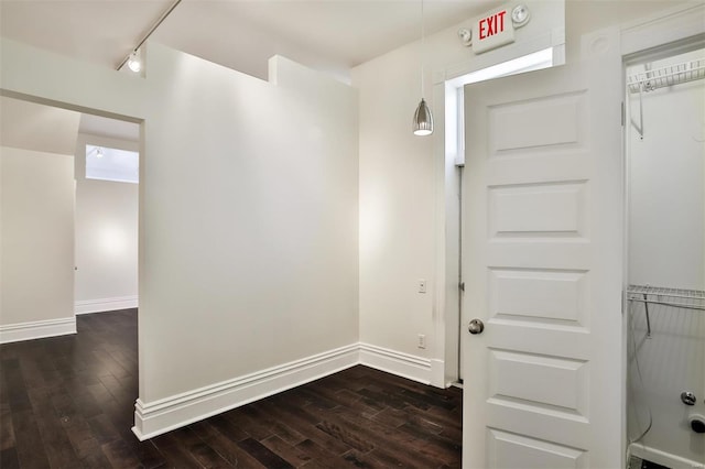 hall with dark hardwood / wood-style flooring and track lighting