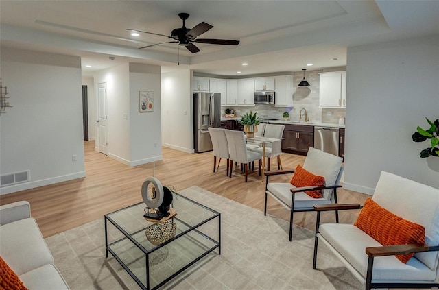 living room with ceiling fan, light hardwood / wood-style floors, and sink