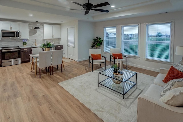 living room featuring ceiling fan, light wood-type flooring, and sink