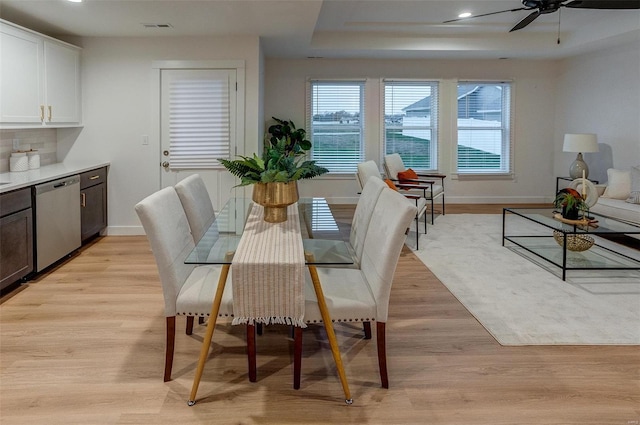 dining room with a tray ceiling, ceiling fan, and light hardwood / wood-style floors