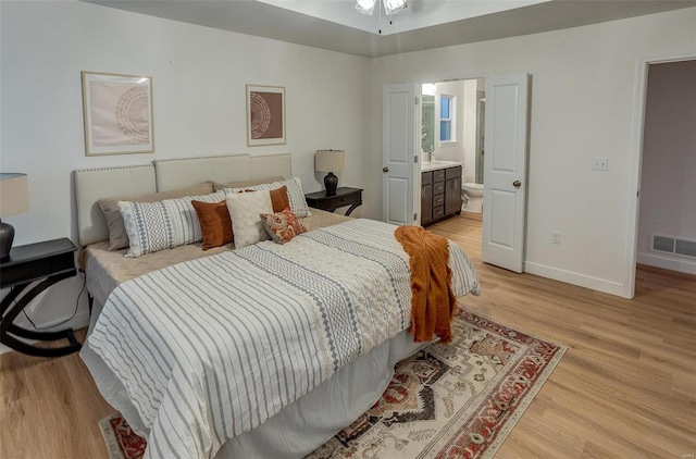 bedroom featuring connected bathroom and light hardwood / wood-style floors