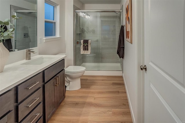 bathroom with hardwood / wood-style flooring, vanity, toilet, and an enclosed shower