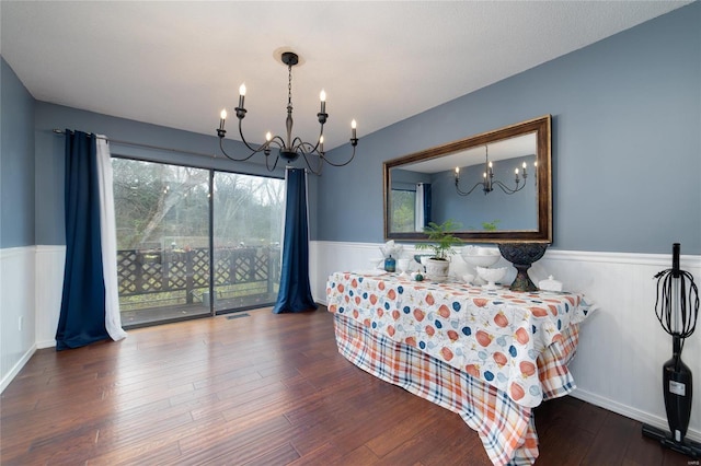 dining space with hardwood / wood-style floors and a notable chandelier