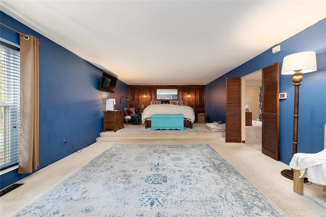 carpeted bedroom featuring ensuite bathroom and wood walls