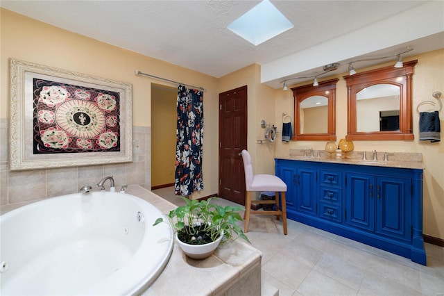 bathroom featuring a skylight, tile patterned floors, vanity, a textured ceiling, and a relaxing tiled tub