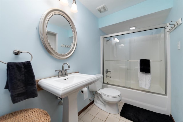 bathroom featuring tile patterned flooring, bath / shower combo with glass door, and toilet