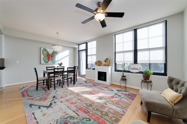 living room featuring ceiling fan with notable chandelier and light hardwood / wood-style flooring