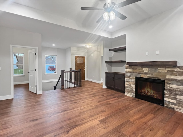 unfurnished living room featuring a stone fireplace, ceiling fan, and hardwood / wood-style floors