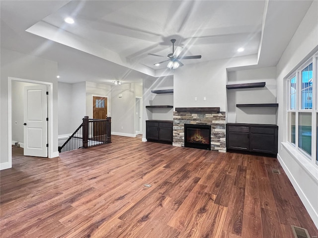 unfurnished living room featuring a fireplace, hardwood / wood-style floors, a tray ceiling, and ceiling fan