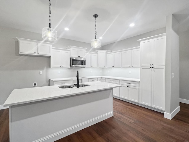 kitchen with white cabinetry, sink, dark hardwood / wood-style flooring, an island with sink, and pendant lighting