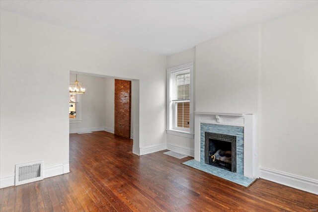 unfurnished living room featuring a fireplace, dark hardwood / wood-style flooring, and an inviting chandelier