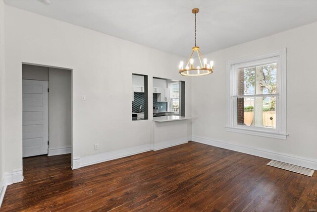 unfurnished dining area with a chandelier and dark hardwood / wood-style floors