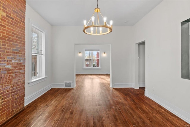 unfurnished dining area with a chandelier and dark hardwood / wood-style floors