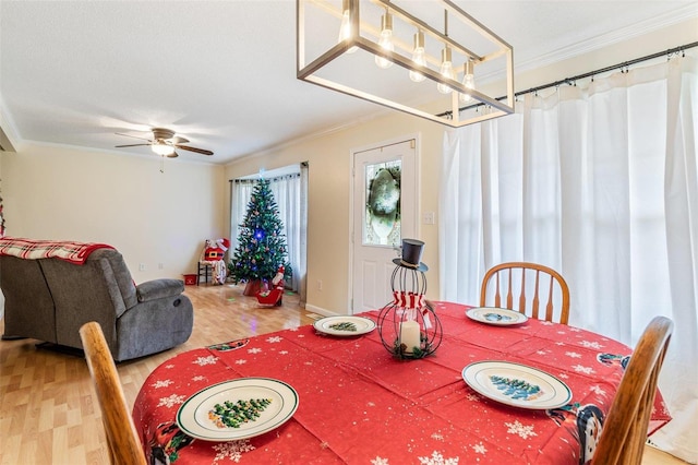 dining space with hardwood / wood-style floors, ceiling fan with notable chandelier, and ornamental molding