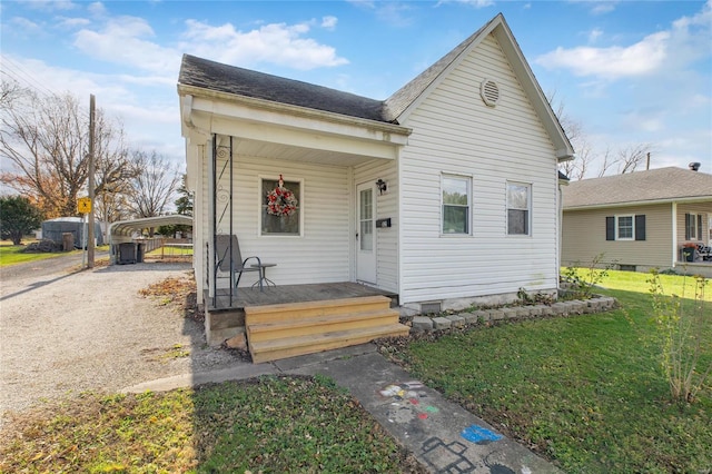 bungalow with a front lawn, a porch, and a carport