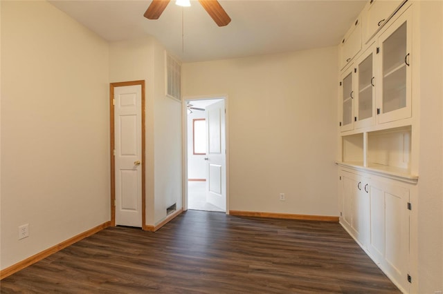 empty room with ceiling fan and dark hardwood / wood-style flooring