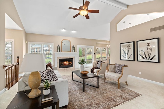 carpeted living room featuring lofted ceiling with beams, ceiling fan with notable chandelier, and a tiled fireplace