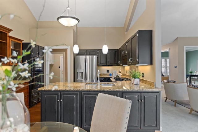 kitchen with light stone countertops, sink, hanging light fixtures, vaulted ceiling, and appliances with stainless steel finishes