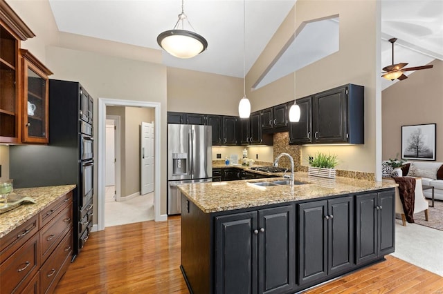 kitchen featuring ceiling fan, tasteful backsplash, light stone counters, stainless steel refrigerator with ice dispenser, and pendant lighting