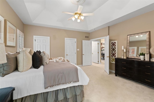 bedroom featuring ceiling fan, a raised ceiling, and light carpet