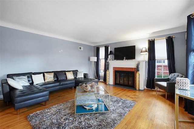 living room with hardwood / wood-style floors and a brick fireplace