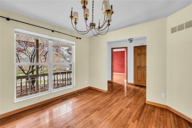 unfurnished dining area featuring light hardwood / wood-style flooring and an inviting chandelier