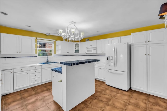 kitchen with white cabinetry, a center island, white appliances, and sink