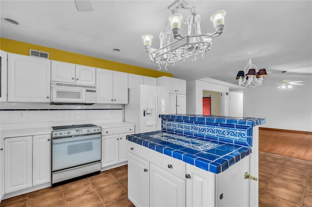 kitchen with a center island, white appliances, ceiling fan with notable chandelier, decorative backsplash, and white cabinetry