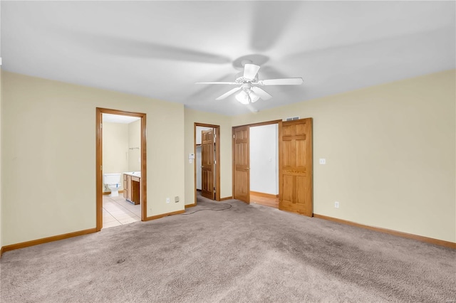 unfurnished bedroom featuring ensuite bathroom, a closet, ceiling fan, and light carpet