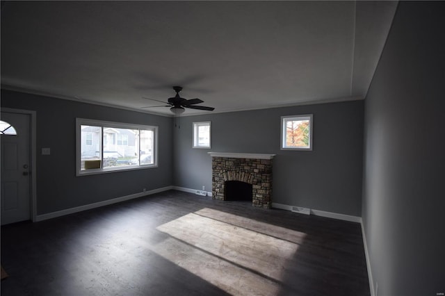 unfurnished living room featuring ceiling fan, dark hardwood / wood-style flooring, and a stone fireplace