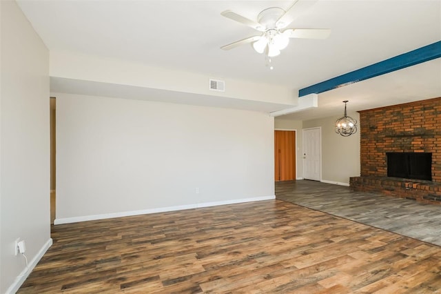 unfurnished living room with ceiling fan with notable chandelier, dark hardwood / wood-style flooring, and a fireplace