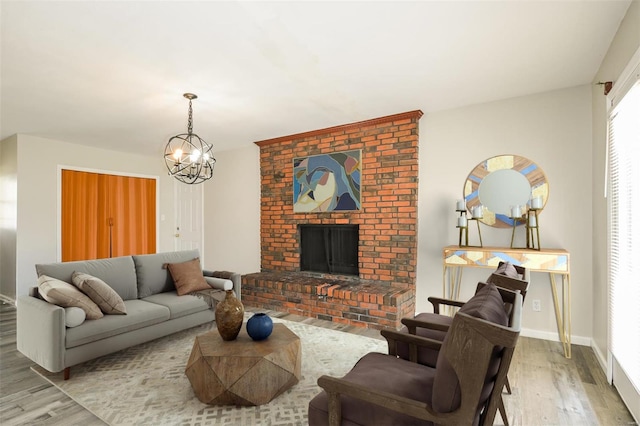 living room with a fireplace, light hardwood / wood-style flooring, and an inviting chandelier