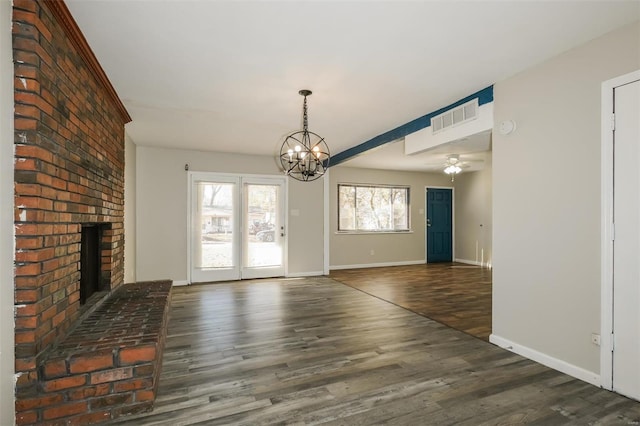 interior space with ceiling fan with notable chandelier, a brick fireplace, and dark wood-type flooring