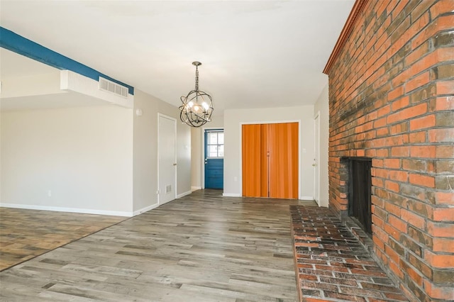 interior space featuring an inviting chandelier, dark wood-type flooring, and a brick fireplace